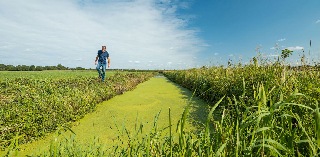 boer die over land loopt naast water